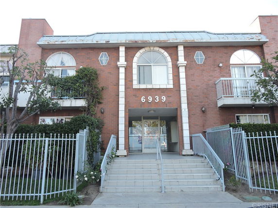 Front view of a two-story brick building with a gated entrance.