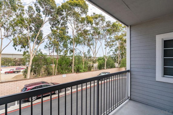 View from a balcony showing trees and parked cars below.
