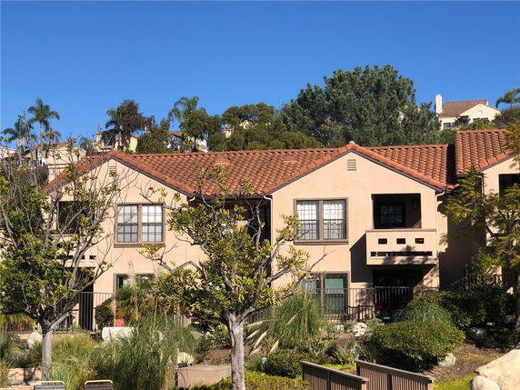 Front view of a two-story house with a red-tiled roof and beige exterior walls.