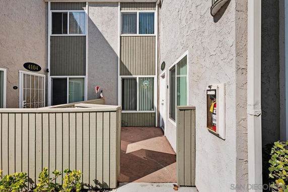 Front view of a multi-story residential building with a small patio area.