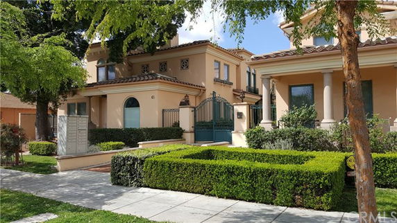 Front view of a two-story house with decorative gate and manicured hedges.
