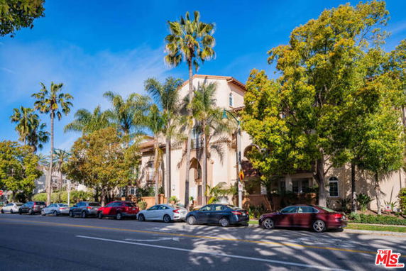 Front view of a multi-story residential building with palm trees.