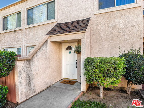 Front view of a beige stucco townhouse entrance with a small overhang.