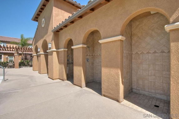 Outdoor view of a building with arched openings and a tiled shower area.
