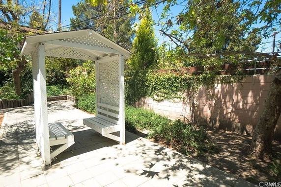 Outdoor view with a white pergola and surrounding greenery.