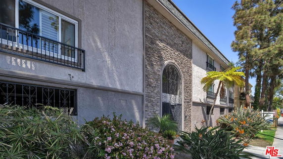 Front view of a multi-story residential building with large windows and stone facade.