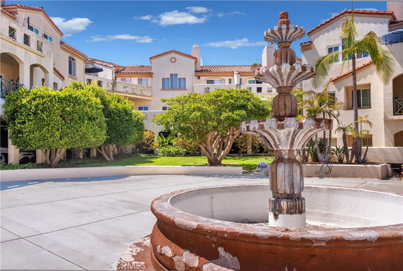Front view of a multi-story building with balconies and a central courtyard featuring a fountain.