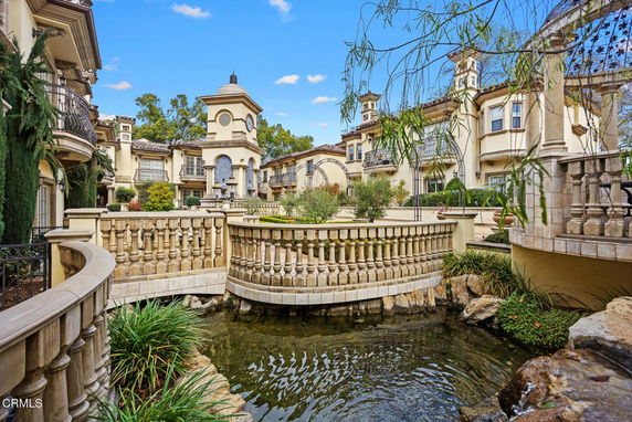 Front view of a luxurious multi-story building with elegant architectural details and a clock tower.