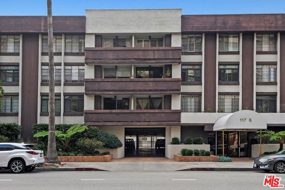 Front view of a multi-story building with balconies and a covered entrance.