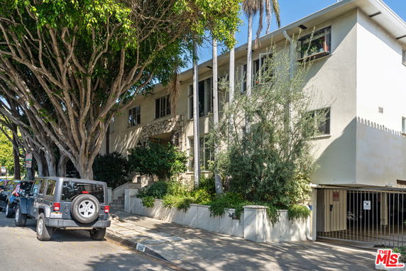 Front view of a two-story apartment building with a gated parking area.
