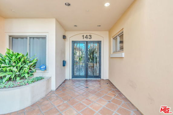 Front view of a building entrance with double glass doors and a tiled walkway.