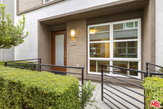 Front view of a house entrance with a modern design, including a glass-paneled door and large windows.