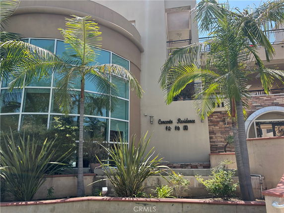 Front view of a multi-story building with large curved windows and palm trees.