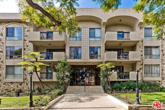 Front view of a multi-story residential building with balconies and a central entrance.