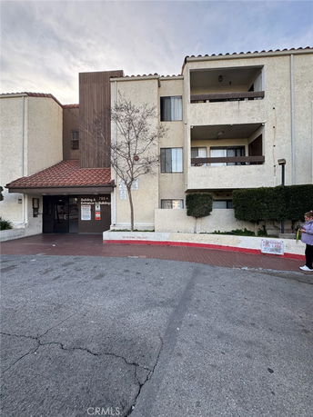 Front view of a multi-story residential building with balconies and a red-tiled roof entrance.