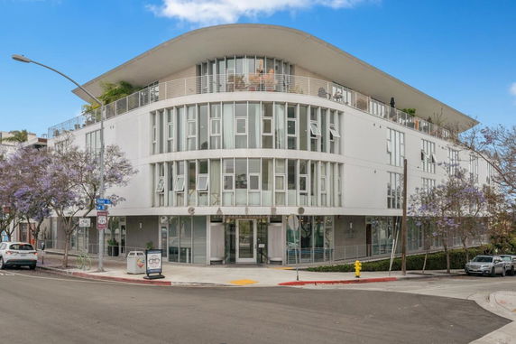 Front view of a modern multi-story building with large windows and a curved roof.