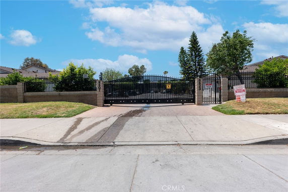 Front view of a gated entrance with brick pillars and metal gate.