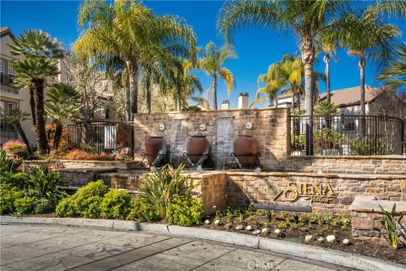 Front view of a residential building complex with stone walls and water features.
