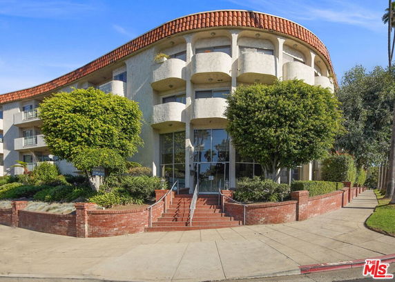 Front view of a multi-story building with a curved facade and red-tiled roof.
