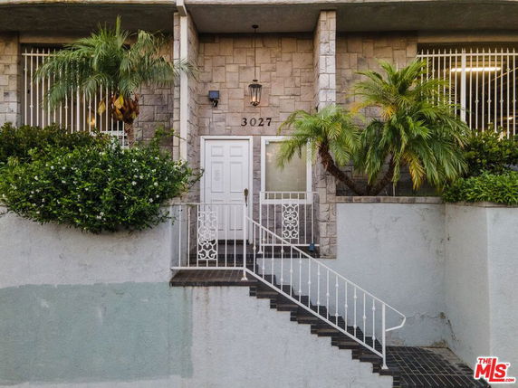 Front view of a house with a stone facade and staircase leading to the entry.