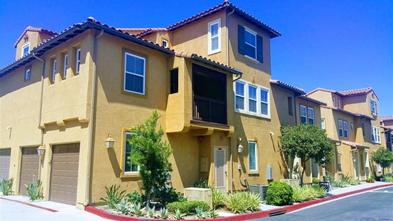 Front view of a multi-story residential building with a tiled roof and garage.