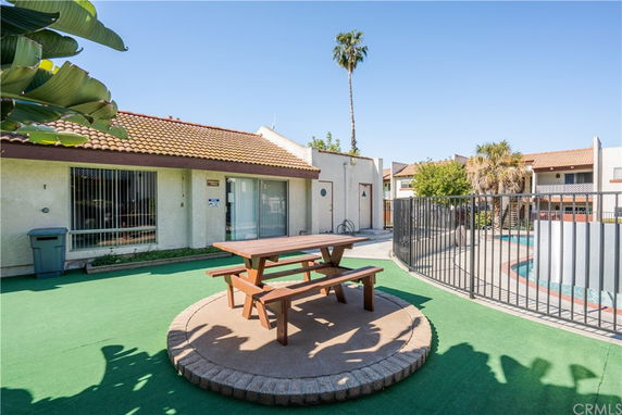 Outdoor area with a fenced swimming pool and a picnic table.