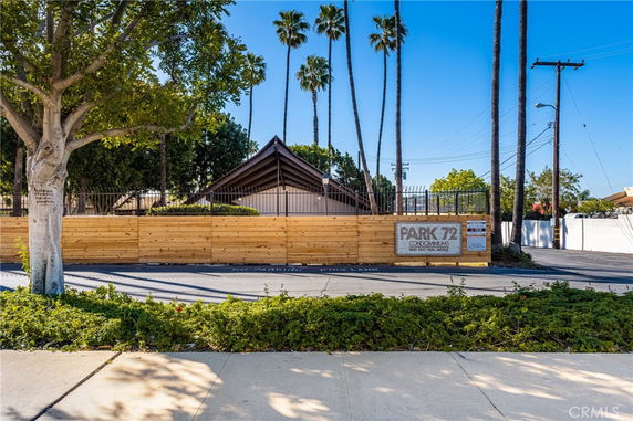 Front view of a condominium complex with a wooden fence and sign.