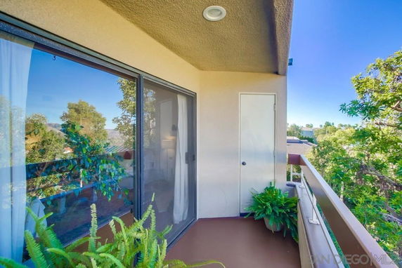 Balcony with sliding glass door and surrounding greenery.