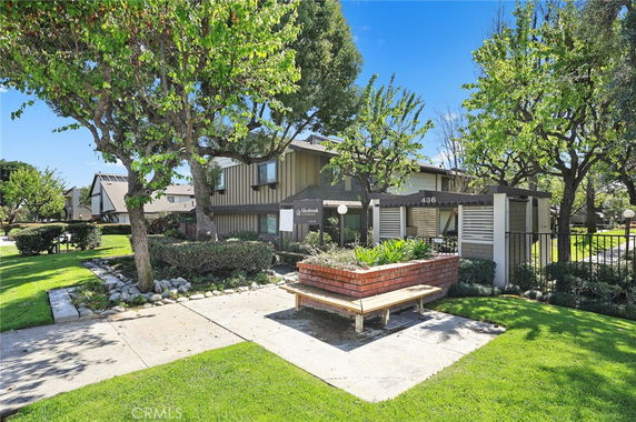 Front view of a two-story residential building with surrounding trees and landscaped area.