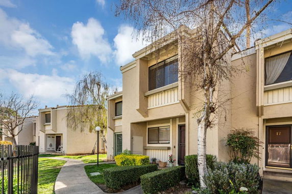 Front view of a multi-story townhouse with beige exterior and large windows.
