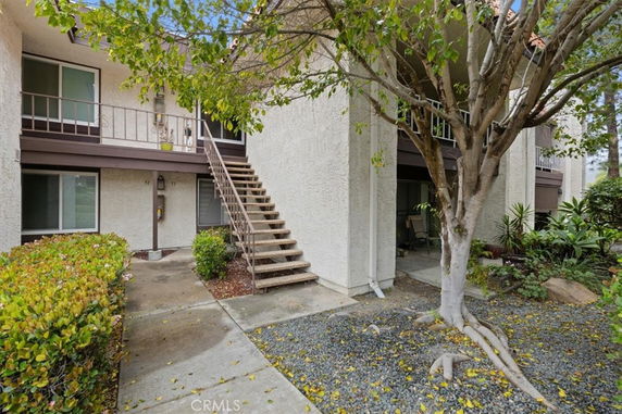 Front view of a two-story building with an external staircase and garden area.