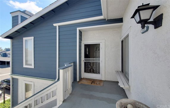 Front view of a building entrance with blue siding and a small porch area.