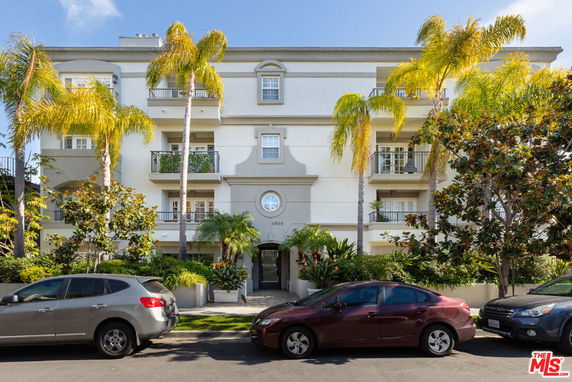 Front view of a multi-story residential building with balconies and palm trees.