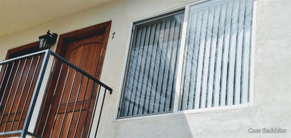 Front view of a building with a balcony and a wooden door.