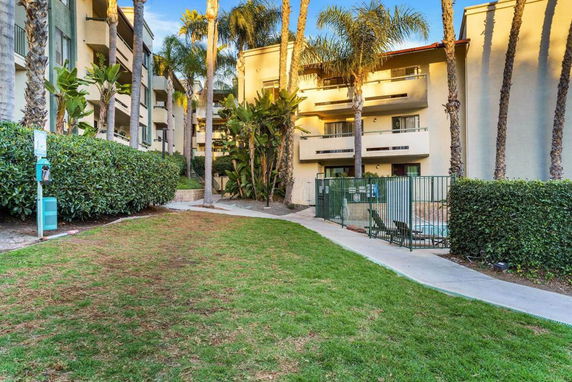 View of a multi-story residential building with balconies and a fenced outdoor area.