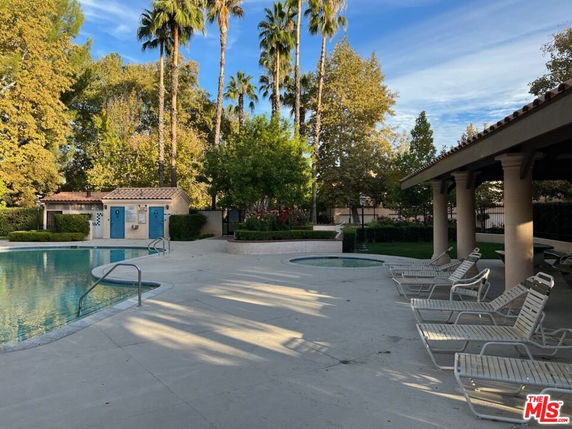 Outdoor swimming pool area with lounge chairs and poolside shelter.