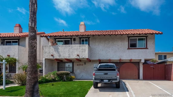 Front view of a two-story house with a garage and a palm tree in front.