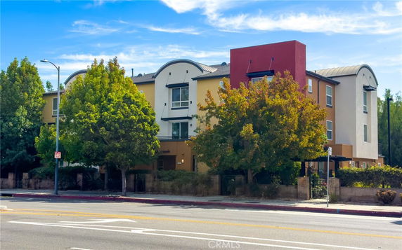 Front view of a multi-story residential building with a distinctive arched roof design.