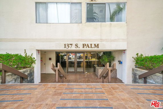 Front view of a building entrance with large glass doors and a sign reading 137 S. PALM.