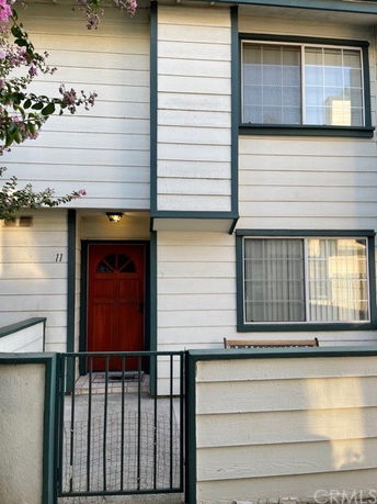 Front view of a two-story house with a red door and grid-patterned windows.