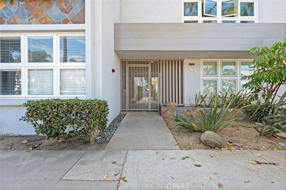 Front view of a building entrance with multiple windows and a sidewalk path leading to a gated entry.