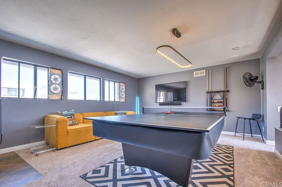 Room with ping pong table, seating area, and wall-mounted TV.