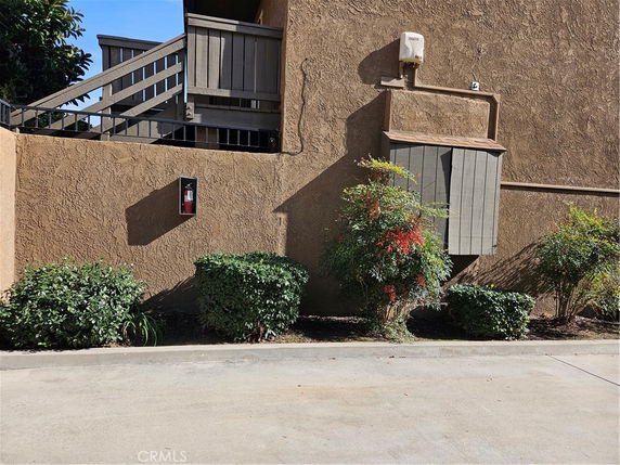 Exterior view of a building with stairs and a fire extinguisher on the wall.