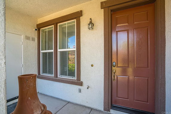 Front view of a house with a brown door and window with shutters.