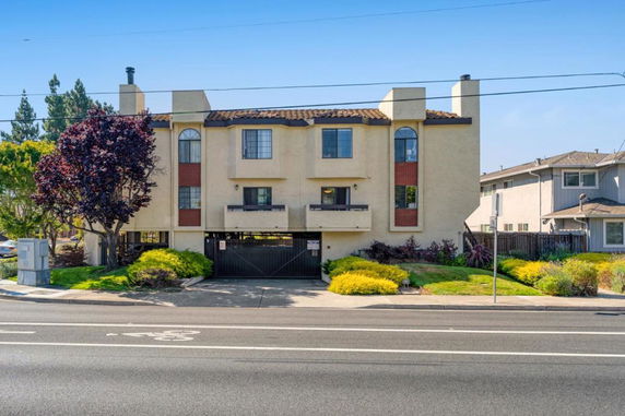 Front view of a three-story apartment building with multiple windows and a gated entrance.