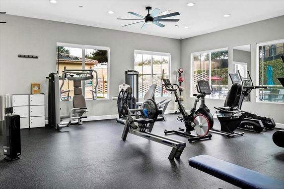 Interior view of a gym with various exercise equipment and large windows.