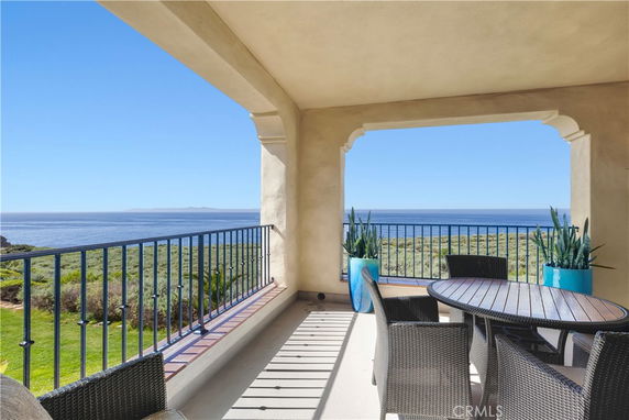 Outdoor patio with table and chairs overlooking the ocean.