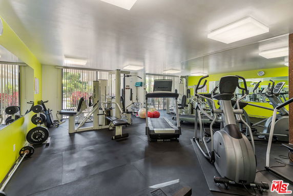 Indoor gym area with various exercise equipment including treadmills and weight machines.