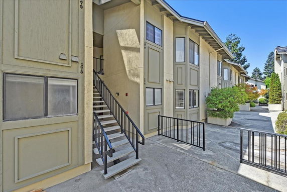 Front view of a multi-story apartment building with stairs and railings.
