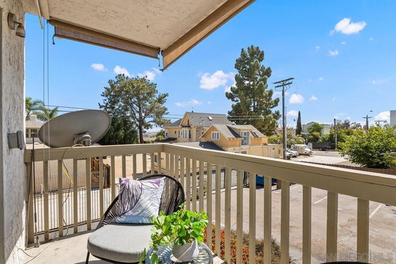 View from a balcony overlooking a residential area with houses and trees.